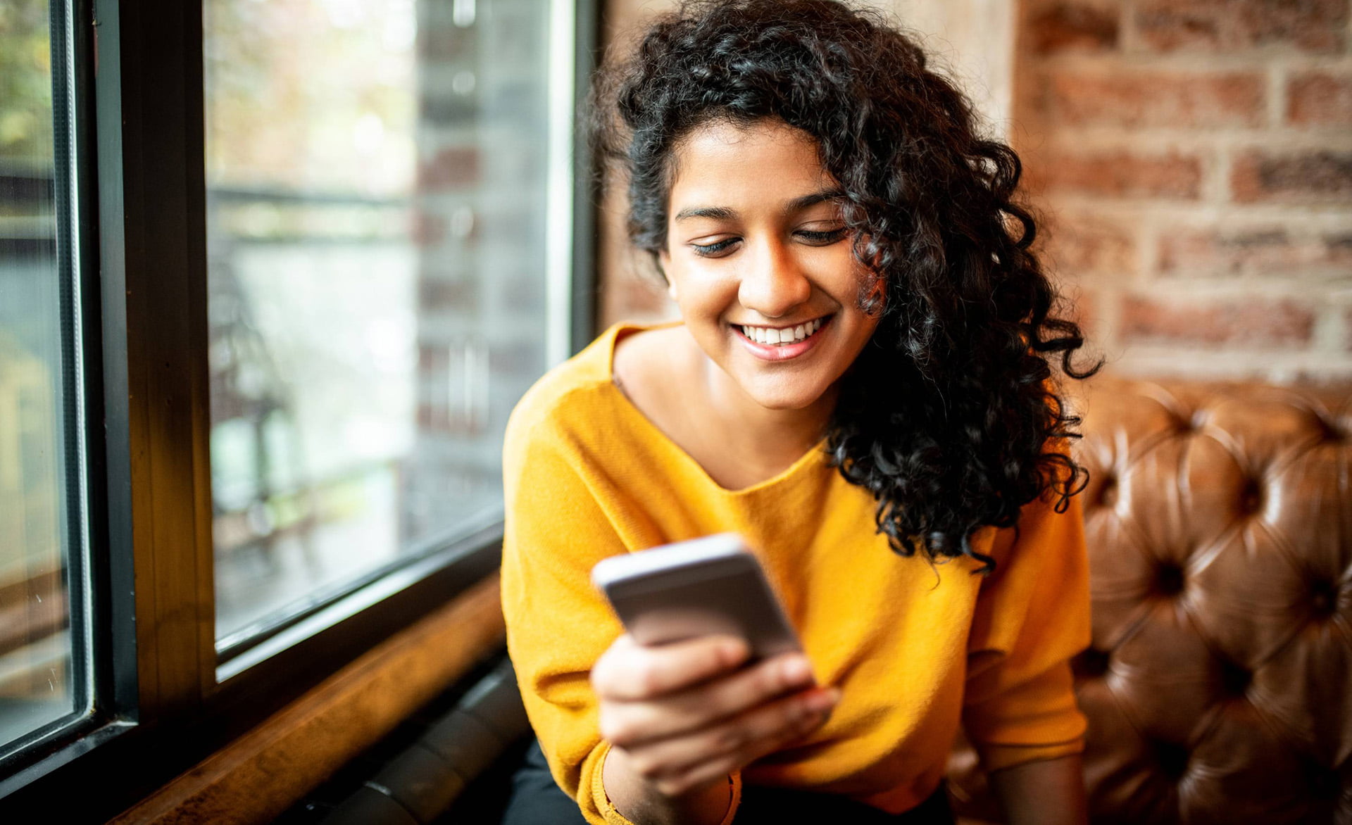 instagram shopping - mulher sorrindo acessando redes sociais através do smartphone