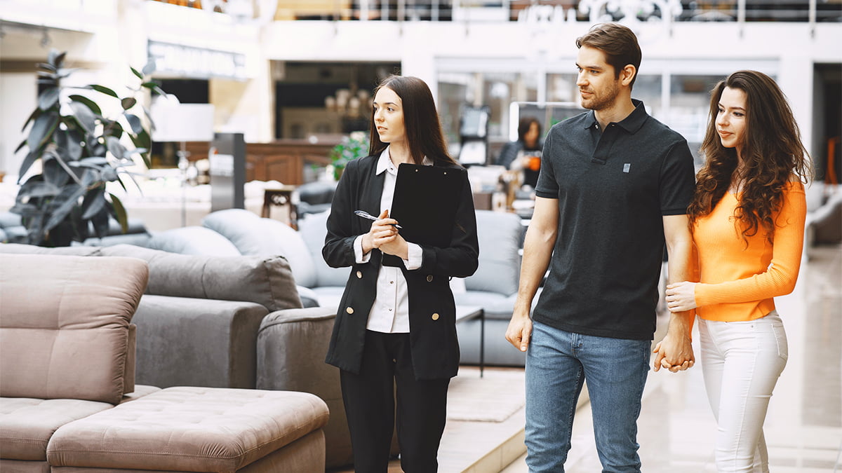 persuasão na estratégia de vendas - vendedora mostrando móveis em uma loja para um casal