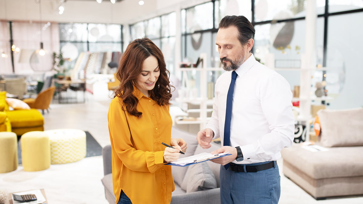 ticket médio - mulher assinando pedido de venda em um showroom ao lado do vendedor