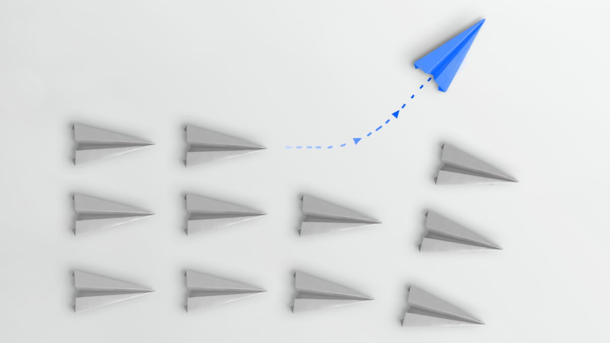 benchmarking - aviões de papel brancos indo para a direita enquanto o avião de papel azul muda de rota e vai para cima