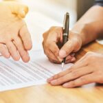 cancelamento de contrato - pessoa assinando contrato junto do vendedor